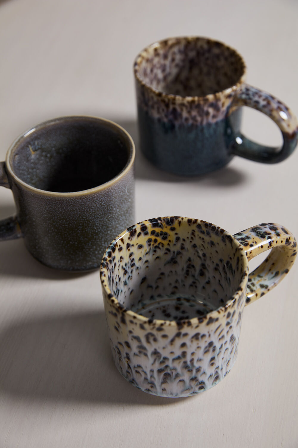 Three ceramic mugs with leopard print patterns on a light background