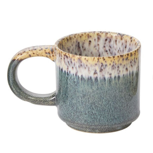 Speckled ceramic mug with a gradient from green to brown on a white background